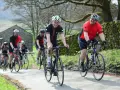 Un groupe de cyclistes souriants roule sur une route de campagne, respectant le code de la route pour cycliste en groupe.