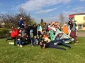 Groupe de jeunes en costumes et déguisements, certains sur une tente, sur l'herbe par beau temps.