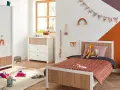 Chambre d'enfant décorée avec un lit, une commode, une armoire et des jouets.