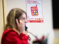 Une femme au téléphone, devant une affiche expliquant le crip signification du numéro 119 pour les enfants en danger.