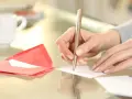 Main tenant rédige un modèle d'autorisation parentale TAM. Une tasse de café et une enveloppe rouge sont à proximité.