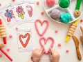 Pâte à modeler rose en forme de cœur, cartes d'activités, rouleaux et petites boules de pâte.