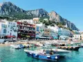 Vue pittoresque de Capri, un joyau pour votre naples voyage. Bateaux colorés dans une eau turquoise, face aux maisons et aux falaises majestueuses.
