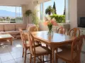 Un salon lumineux avec canapé, table à manger et vue sur les montagnes. Idéal pour imaginer comment partir en famille d'accueil.