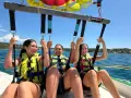 Trois jeunes femmes souriantes en parachute ascensionnel au-dessus de la mer.