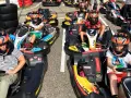 Des enfants casqués prêts pour une course de colo karting, le sourire aux lèvres, impatients de démarrer.