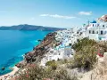 Vue panoramique de Santorin, Grèce, avec des maisons blanches et des dômes bleus surplombant la mer Égée.