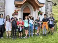 Groupe d'enfants en tenue de randonnée devant une petite église en montagne.