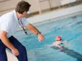Entraîneur surveillant un nageur, peut-être pour un certificat de natation pour colonie.