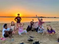 Groupe d'enfants joyeux sur une plage au coucher du soleil.