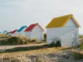 Cabanes de plage colorées à Gouville-sur-Mer : découvrez les activités nautiques et les promenades sur le sable.