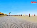 Plage de Deauville, parfaite pour une vacance scolaire en Normandie. Cabines colorées, parasols et ciel bleu azur.