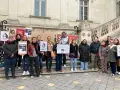 Un groupe de personnes manifeste devant un bâtiment, tenant des pancartes "Le Ministère de l'injustice".