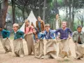 Des enfants participent à une course en sac dans un camp de vacances en forêt.