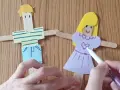 Poupées en bâtonnets de bois, une fille et un garçon, décorées par des mains d'enfant.