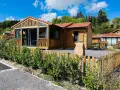 Chalets en bois avec clôture et végétation devant, sous un ciel bleu.