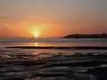Coucher de soleil sur la mer à Saint-Pair-sur-Mer. La lumière dorée illumine le ciel et l'eau, invitant à la contemplation.
