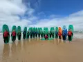 Groupe de jeunes souriants avec des planches de surf sur une plage.