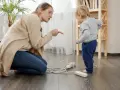 Une femme réprimande un enfant près de prises électriques au sol.