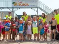 Un groupe d'enfants joyeux, portant des foulards orange, pose pour une photo de famille lors de leurs vacances.