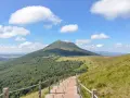 Escalier en bois menant au Puy de Dôme sous un ciel bleu et nuageux.