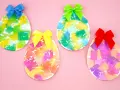 Quatre œufs décorés de papier crépon coloré et ornés de rubans sur fond rose.
