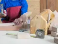 Enfant bricolant avec un marteau, des clous, un mètre ruban et des outils en bois.