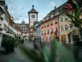 Vue d'une rue pavée à Fribourg-en-Brisgau avec une tour à horloge et des bâtiments colorés.
