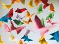 Papillons en origami multicolores flottant sur fond clair.