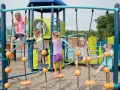 Enfants jouant sur une structure d'escalade avec des cordes et des balles oranges.