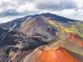 Vue aérienne de l'Etna, avec ses cratères rouges et ses pentes noires et vertes.
