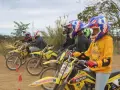Jeunes pilotes prêts pour une course de moto cross. Casques colorés et motos jaunes alignées.