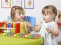 Deux petites filles s'amusent avec un xylophone, explorant la musique et les activités manuelles.