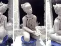 Sculpture en argile d'une jeune fille aux cornes, assise, vêtue d'une tunique ajourée.