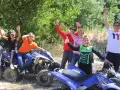 Des enfants joyeux sur des quads, bras levés, en extérieur.