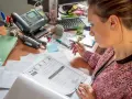 Une femme examine un document BAFA sur un bureau encombré.