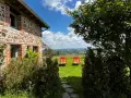 Maison en pierre avec vue panoramique sur les collines, deux chaises longues rouges invitent à la détente. Parfait pour découvrir les destinations Rhône-Alpes.