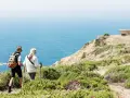Couple randonnant sur les falaises de Jersey, profitant d'un séjour linguistique et d'une vue imprenable sur la mer.