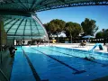 Piscine intérieure avec toboggan bleu, lignes de nage et quelques personnes.