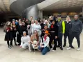 Un groupe de jeunes gens, certains déguisés, pose pour une photo dans un hall moderne.
