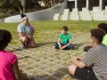Une animatrice discute avec des enfants assis en cercle dans un parc.