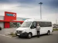 Un homme pose à côté d'un minibus 9 places permis B, devant un Super U.