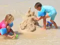 Enfants construisant un château de sable, une scène typique d'accueil centre de loisirs en bord de mer.