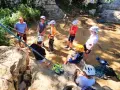 Des jeunes en pleine colonie de vacances escalade, casques blancs et jaunes, prêts pour l'aventure sur les rochers.