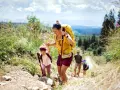 Famille faisant de la randonnée en montagne, une mère aide sa fille à monter un sentier.