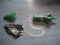 Fusée à eau verte avec cône, parachute noir et fils blancs sur fond gris.