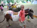 Enfants avec des poneys décorés de peinture, dans un campement avec des tentes.
