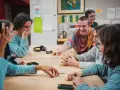 Des jeunes rient en jouant à un jeu de cartes autour d'une table.