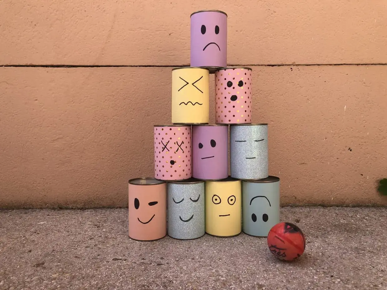 Pyramide de boîtes décorées de visages pour une kermesse chamboule tout. Un dessin amusant prêt à être renversé !