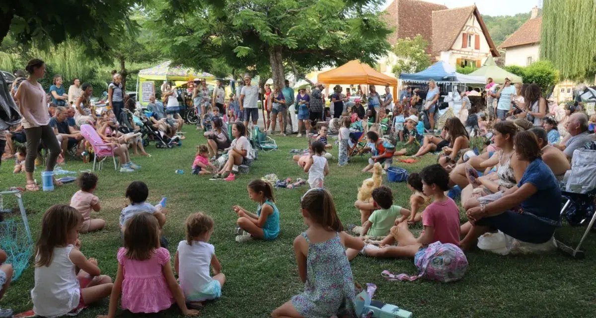 Une foule joyeuse, petits et grands, profite d'une fête de village. Une belle idée animation fête de village, avec des stands et des gens assis sur l'herbe.